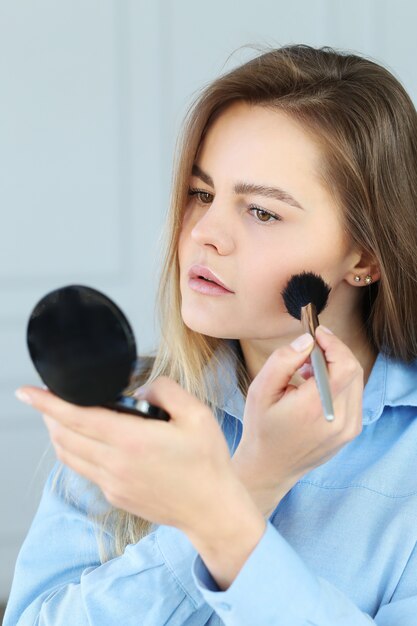 Mujer joven poniéndose maquillaje.