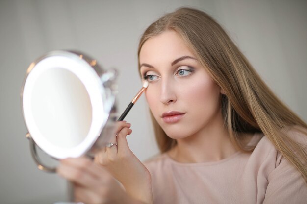 Mujer joven poniéndose maquillaje.