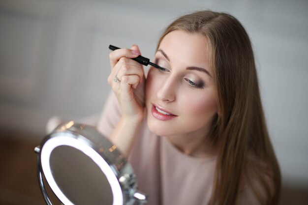 Mujer joven poniéndose maquillaje.