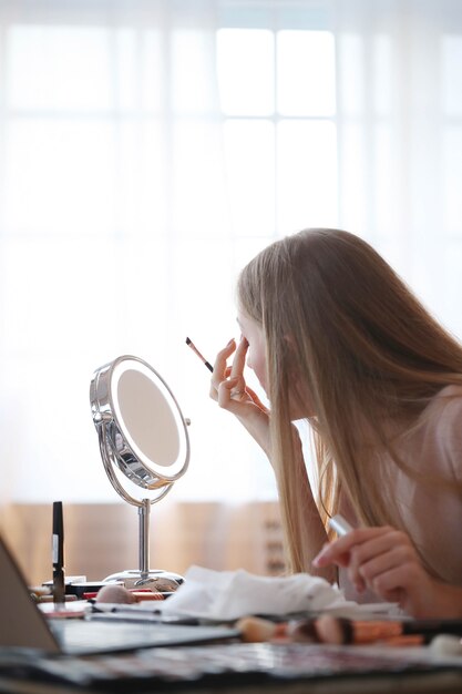 Mujer joven poniéndose maquillaje.