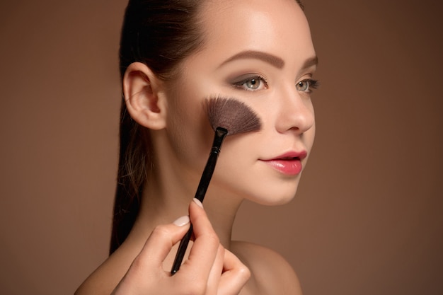 Mujer joven poniéndose maquillaje