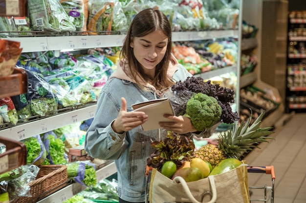 Una mujer joven con un portátil compra alimentos en el supermercado