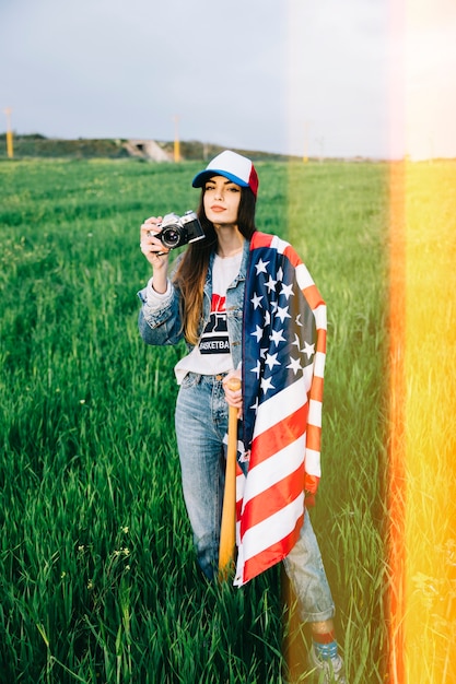 Mujer joven posando en campo con cámara vintage