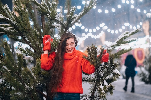 Mujer joven posando cerca del árbol de Navidad en la calle