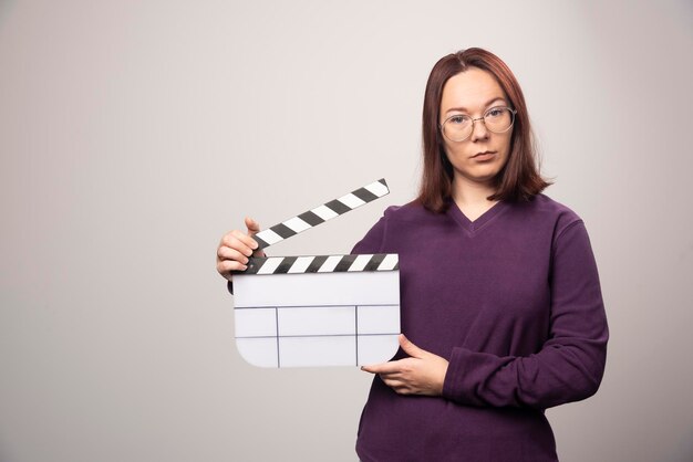 Mujer joven posando con una cinta de cine sobre un fondo blanco. Foto de alta calidad