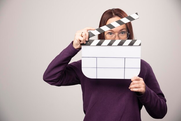 Mujer joven posando con una cinta de cine sobre un fondo blanco. Foto de alta calidad