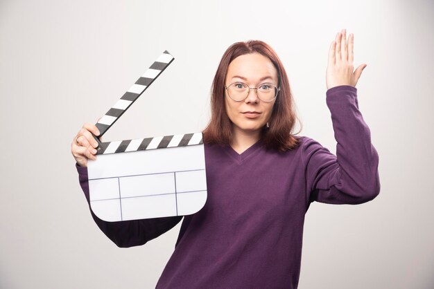 Mujer joven posando con una cinta de cine sobre un fondo blanco. Foto de alta calidad