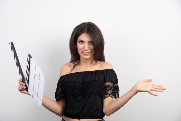 Mujer joven posando con una claqueta de cine.