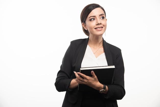 Mujer joven posando con cuaderno sobre fondo blanco. Foto de alta calidad