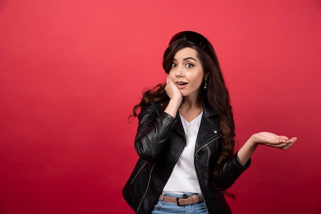 Mujer joven posando con gafas negras sobre un fondo rojo. Foto de alta calidad