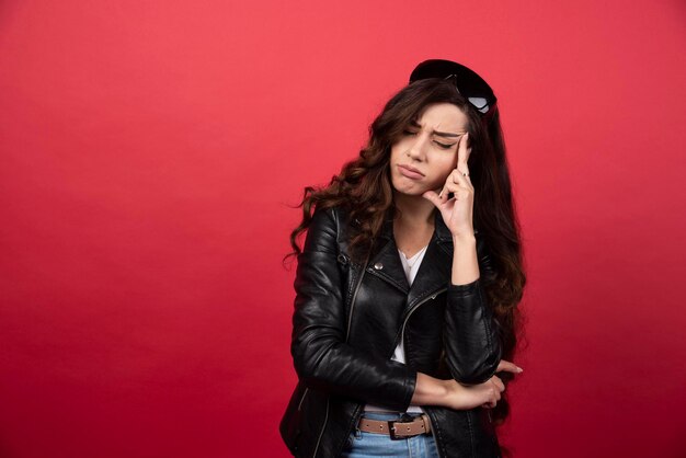 Mujer joven posando con gafas negras sobre un fondo rojo. Foto de alta calidad