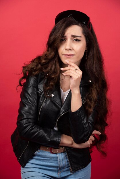 Mujer joven posando con gafas negras sobre un fondo rojo. Foto de alta calidad