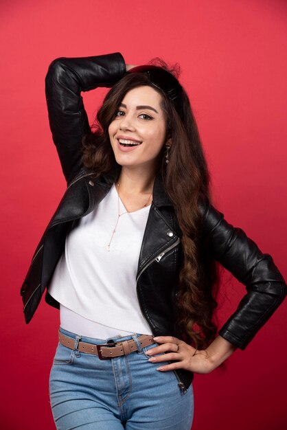 Mujer joven posando con gafas negras sobre un fondo rojo. Foto de alta calidad