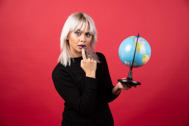 Mujer joven posando con un globo sobre un fondo rojo. foto de alta calidad