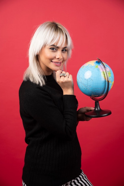 Foto gratuita mujer joven posando con un globo sobre un fondo rojo. foto de alta calidad