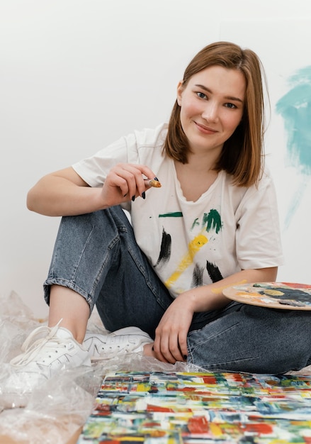 Mujer joven posando junto a su colorida pintura