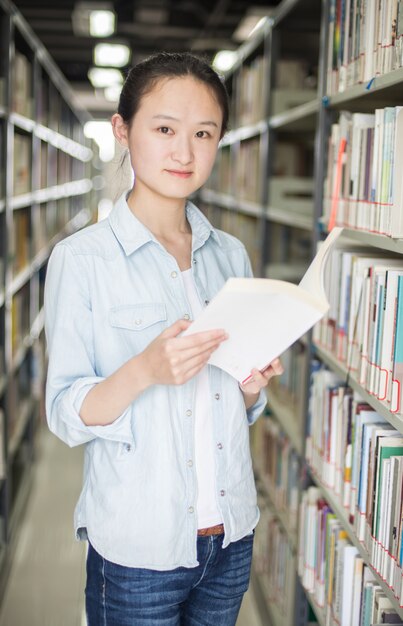 Foto gratuita mujer joven posando con un libro en la biblioteca