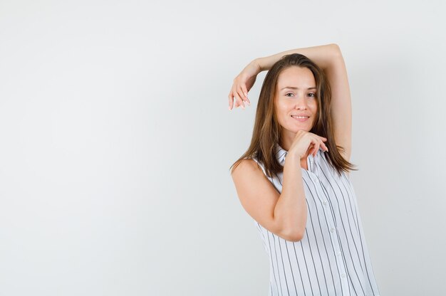 Mujer joven posando mientras mira a la cámara en camiseta y luciendo elegante, vista frontal.