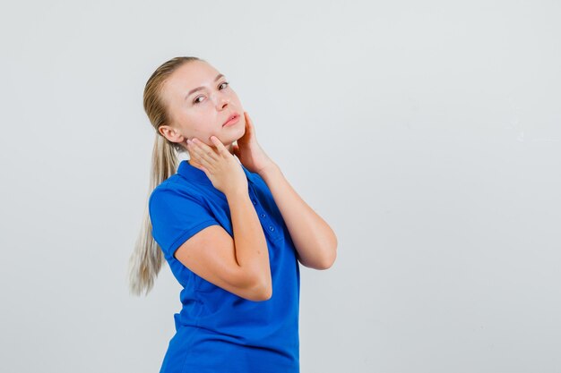 Mujer joven posando mientras mira en camiseta azul y parece encantador