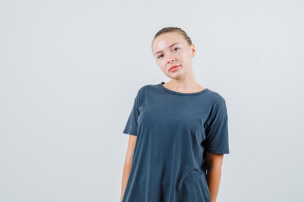 Mujer joven posando mientras mira en camiseta gris.