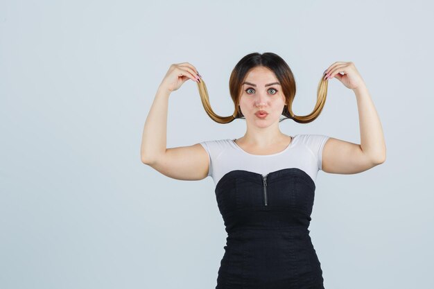 Mujer joven posando mientras sostiene mechones de su cabello