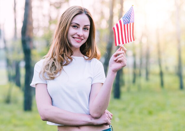 Mujer joven posando con una pequeña bandera de Estados Unidos.