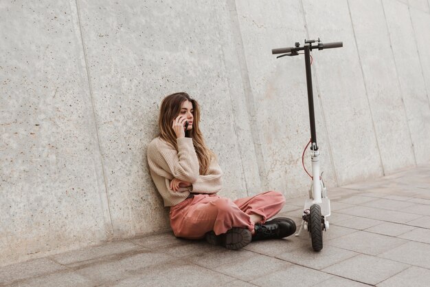 Mujer joven posando con un scooter eléctrico