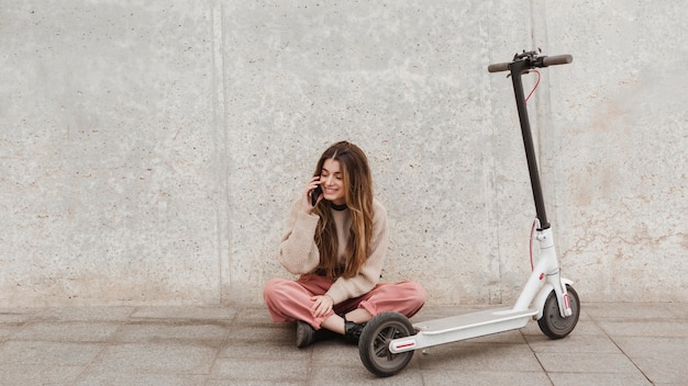 Foto gratuita mujer joven posando con un scooter eléctrico