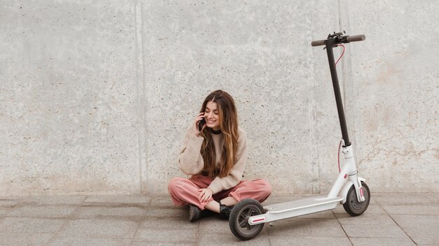 Mujer joven posando con un scooter eléctrico