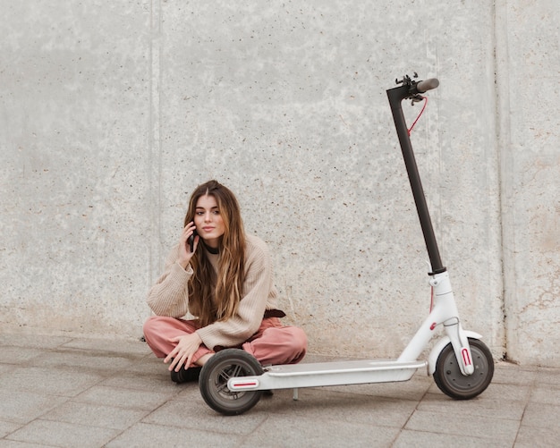 Foto gratuita mujer joven posando con un scooter eléctrico