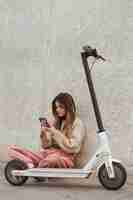 Foto gratuita mujer joven posando con un scooter eléctrico