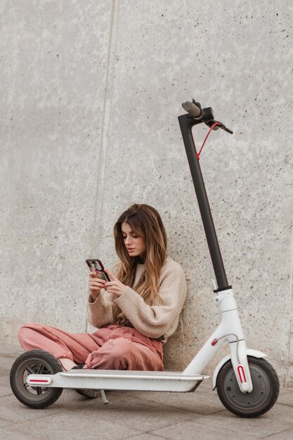 Mujer joven posando con un scooter eléctrico
