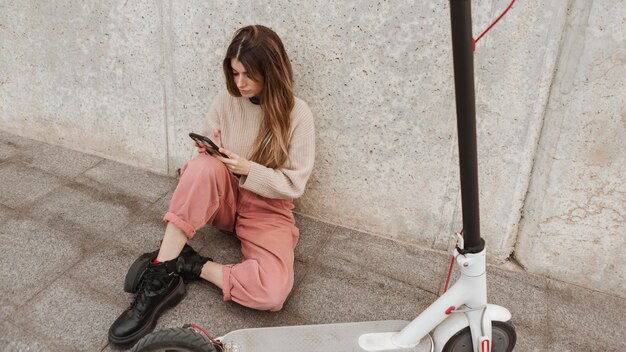 Mujer joven posando con un scooter eléctrico