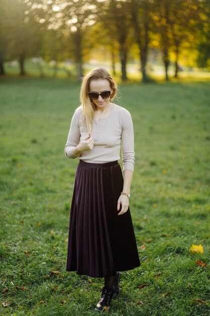 Mujer Joven Posando Sobre Hojas Amarillas En El Parque De Otoño. Al aire libre