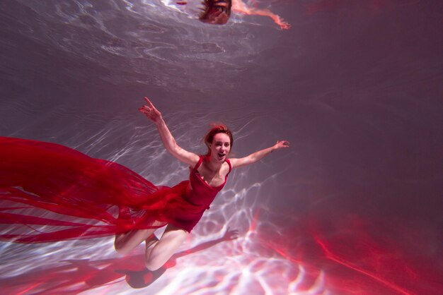 Mujer joven posando sumergido bajo el agua con un vestido fluido