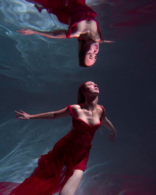 Mujer joven posando sumergido bajo el agua con un vestido fluido