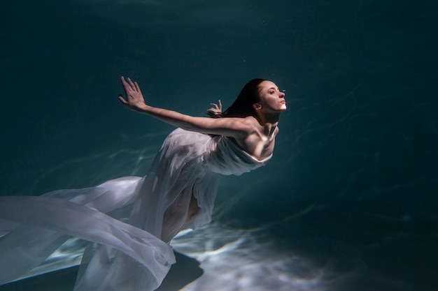 Mujer joven posando sumergido bajo el agua con un vestido fluido