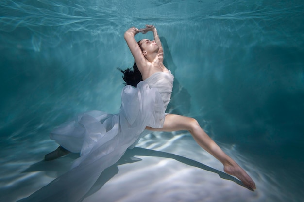 Mujer joven posando sumergido bajo el agua con un vestido fluido