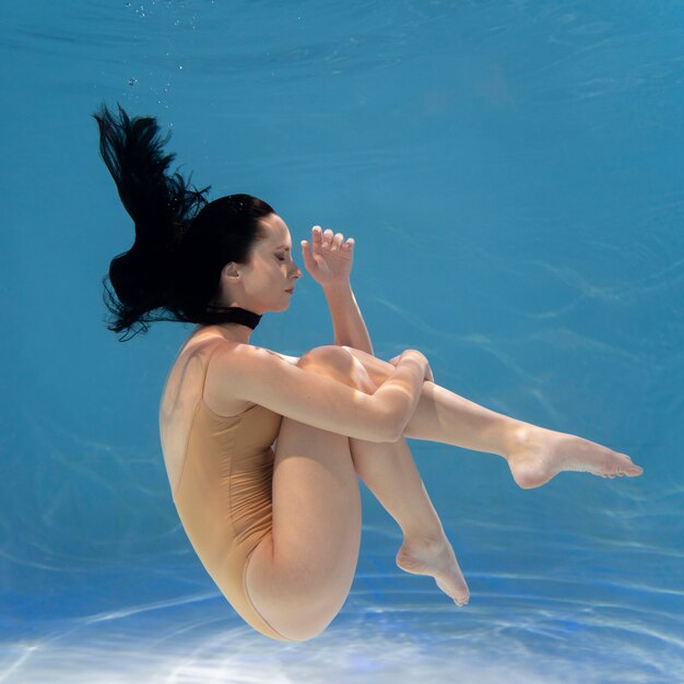 Mujer joven posando sumergido bajo el agua con un vestido fluido