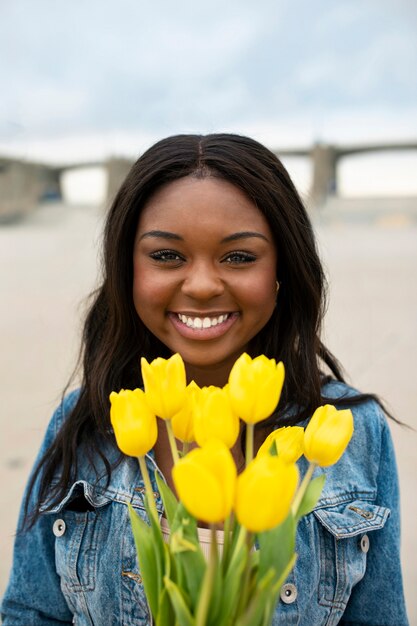 Foto gratuita mujer joven posando con tulipanes mientras está en la ciudad