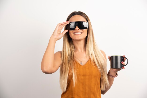 Mujer joven posando con vasos y taza negra.