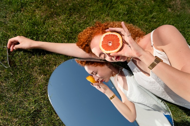 mujer joven, posar, con, pomelo, en, el, espejo, en, pasto o césped