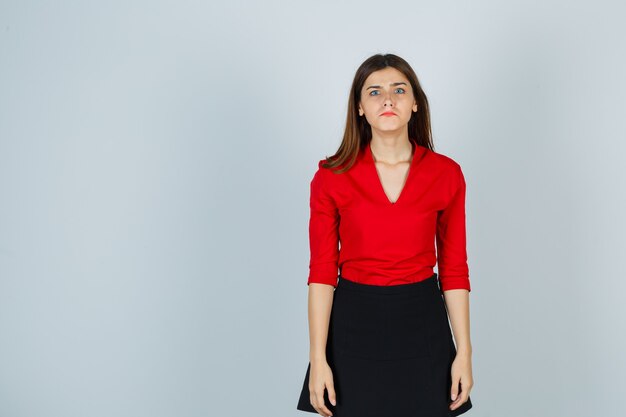 Mujer joven, posición, derecho, mientras, posar, en, blusa roja