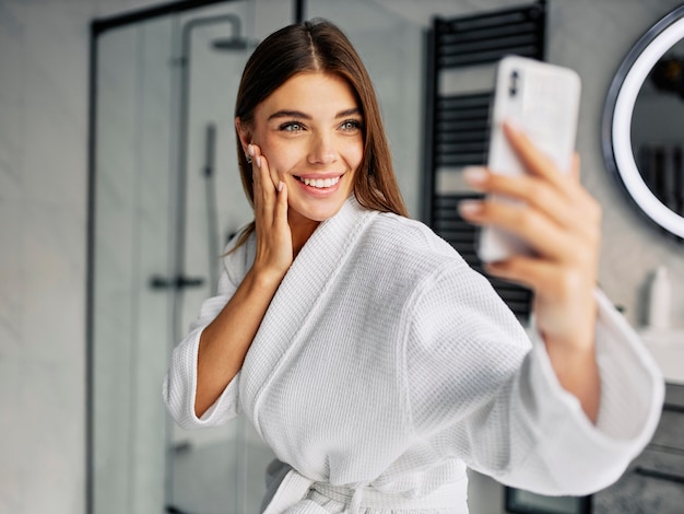 Mujer joven positiva en una bata de baño tomando un selfie