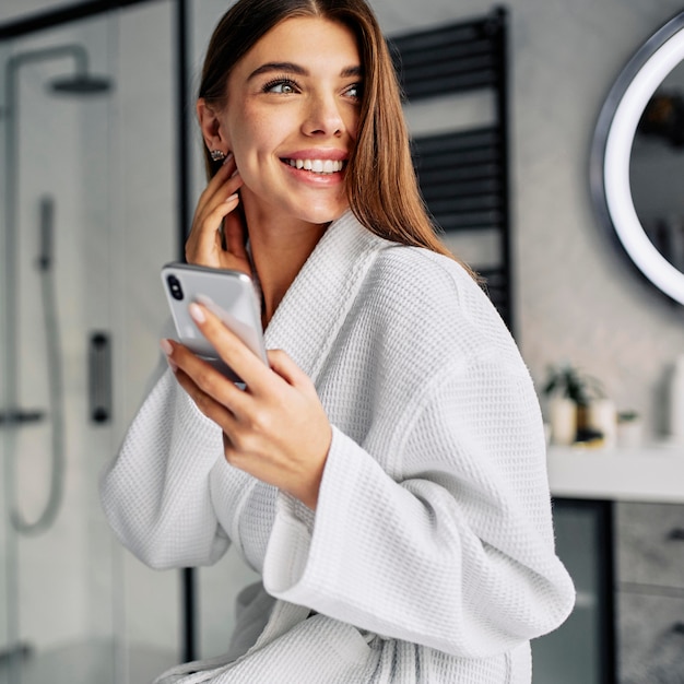 Foto gratuita mujer joven positiva en bata de baño