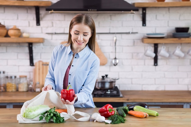 Mujer joven positiva orgullosa de vegetales orgánicos