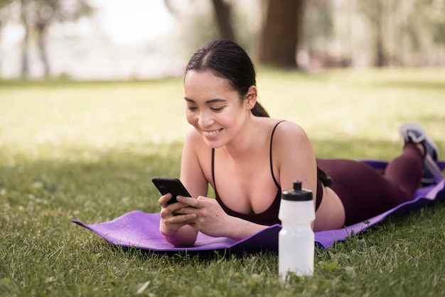 Mujer joven positiva que hojea el teléfono móvil