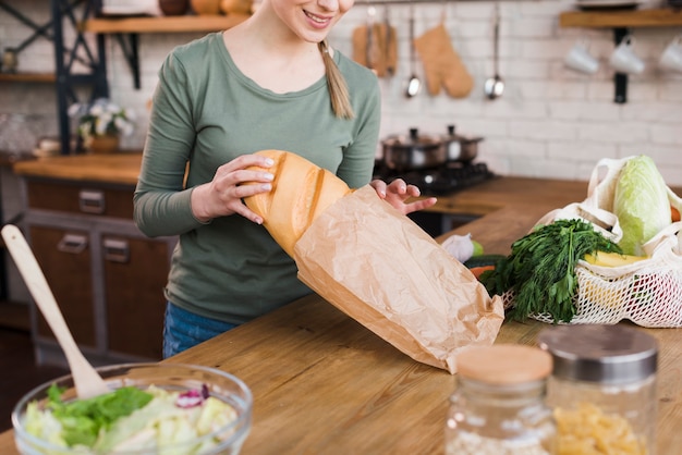 Mujer joven positiva que sostiene el pan fresco
