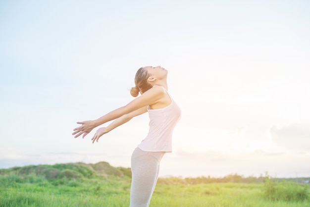 Mujer joven practicando posturas de yoga al aire libre