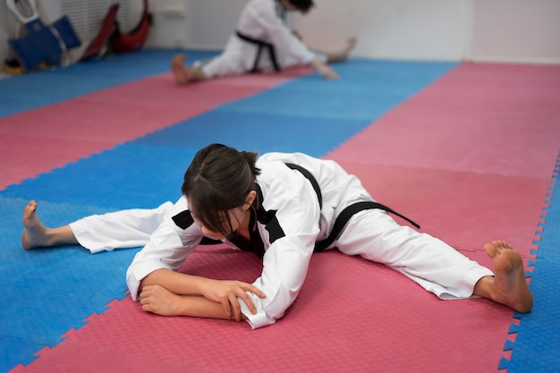 Foto gratuita mujer joven practicando taekwondo en un gimnasio